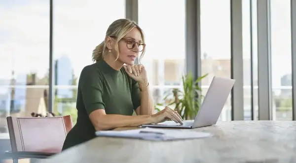 Kobieta w okularach pracuje na laptopie, szukając informacji, jak założyć konto w BIK.