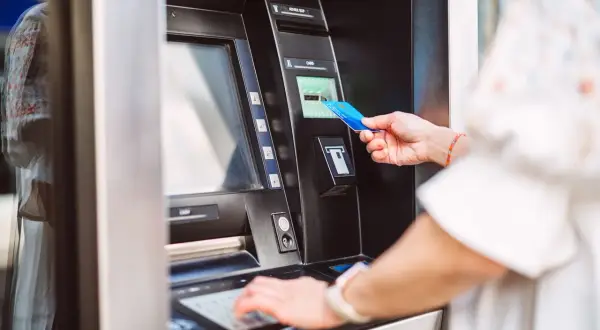 Kobieta wkłada kartę do bankomatu Alior Bank. Korzystaj z bankomatów bez prowizji.