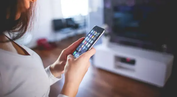 Kobieta trzyma telefon, szukając informacji, jak wyłączyć pakiet komfort Peako.