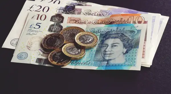 Brytyjskie funty szterlingi, w tym banknoty 5, 10 i 20 funtów, oraz monety. To odpowiedź na pytanie, jaka waluta w Szkocji.