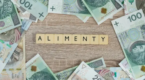 Litery "ALIMENTY" na tle polskich banknotów. Pytanie: ile wynoszą alimenty z funduszu alimentacyjnego?