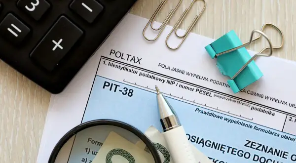 Formularz PIT-38, lupa, długopis i banknoty. Przygotowanie do rozliczenia podatku, by wiedzieć, jak wypłacić pieniądze z funduszu inwestycyjnego.