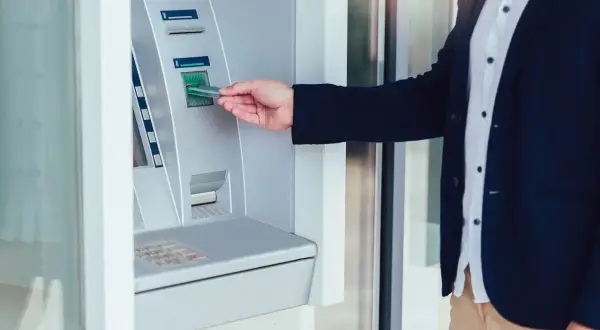 Mężczyzna wkłada kartę do wpłatomatu Peako, aby wpłacić pieniądze.