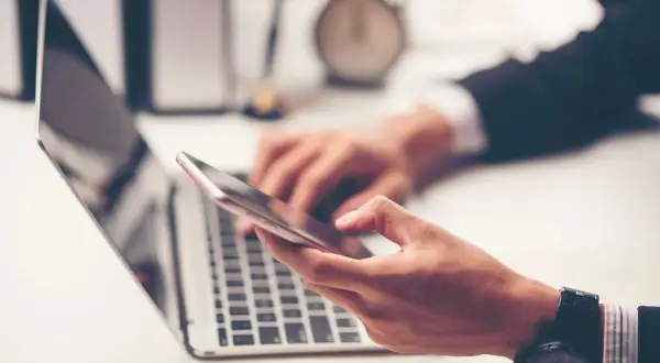 Biznesmen korzysta z telefonu i laptopa, planując przelewy Millenium.
