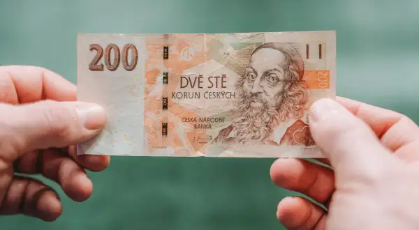 Dwieście koron czeskich, czyli jaka waluta jest w Czechach, trzymane w dłoniach.