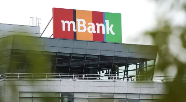 Kolorowy szyld z napisem mBank na dachu nowoczesnego budynku. To siedziba banku, do kogo należy mbank, jest jasne dla każdego.