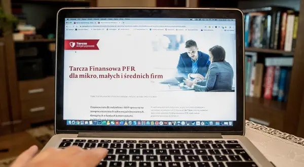 Szukasz informacji, jak sprawdzić czy firma dostała dofinansowanie z tarczy? Na ekranie laptopa wyświetla się strona o Tarczę Finansową PFR dla mikro, małych i średnich firm.