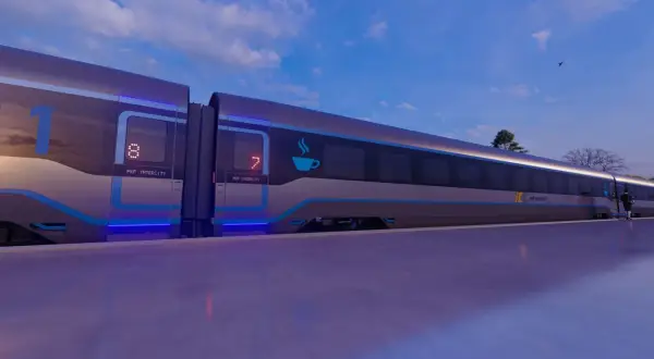 Nowoczesny pociąg PKP Intercity z niebieskimi akcentami i podświetlanymi numerami wagonów na tle nieba.