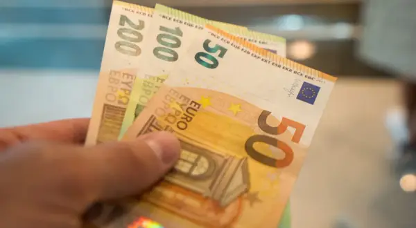 Dłoń trzyma banknoty 50, 100 i 200 euro. Od 2015 roku jaka waluta na Litwie to euro.