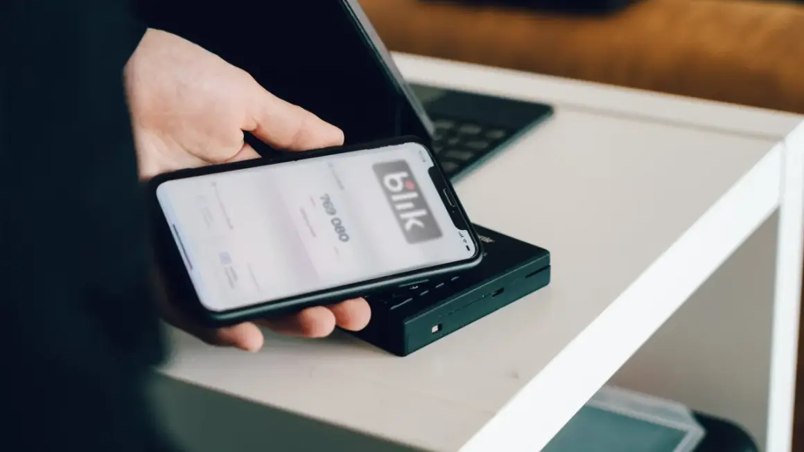 Dłoń trzyma smartfon z aplikacją Blik. Dowiedz się, jak zmienić limit Blik w Millenium, by bezpiecznie zarządzać finansami.