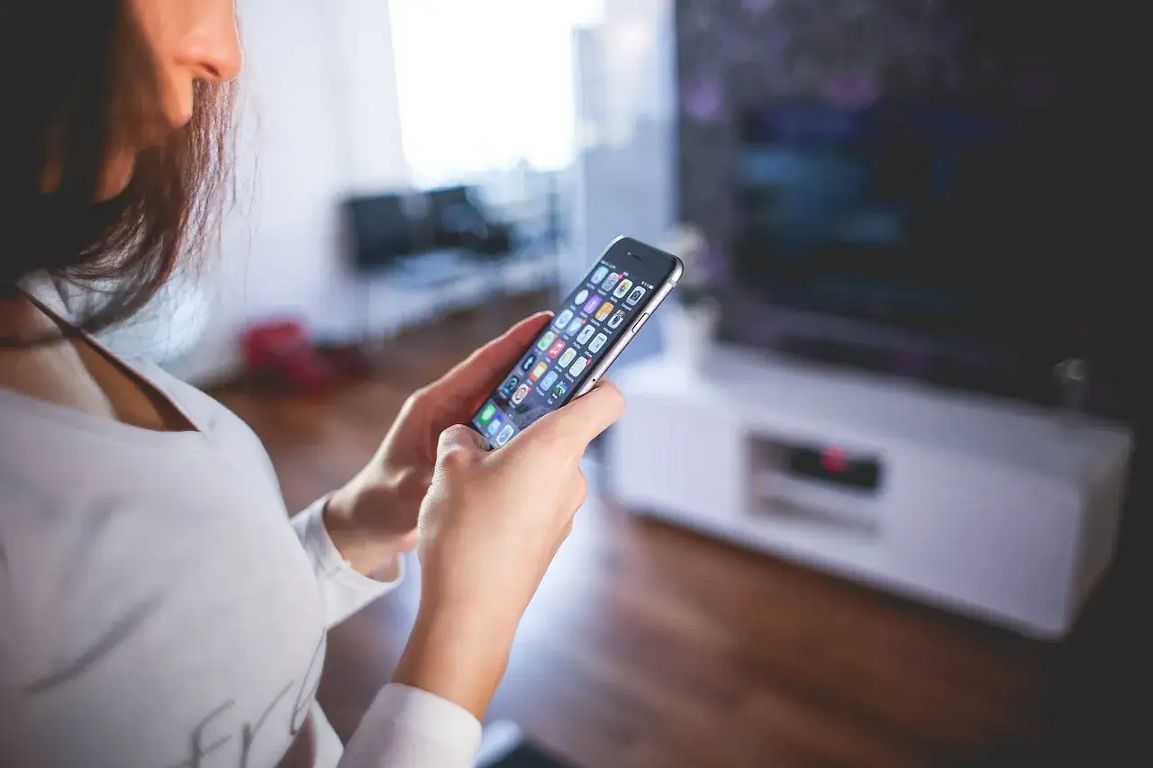 Kobieta trzyma smartfon, szukając informacji, jak wyłączyć pakiet komfort Peako.