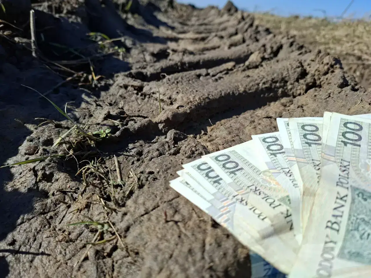 Pieniądze leżą na błotnistej drodze, sugerując, kto dostanie dofinansowanie do węgla.