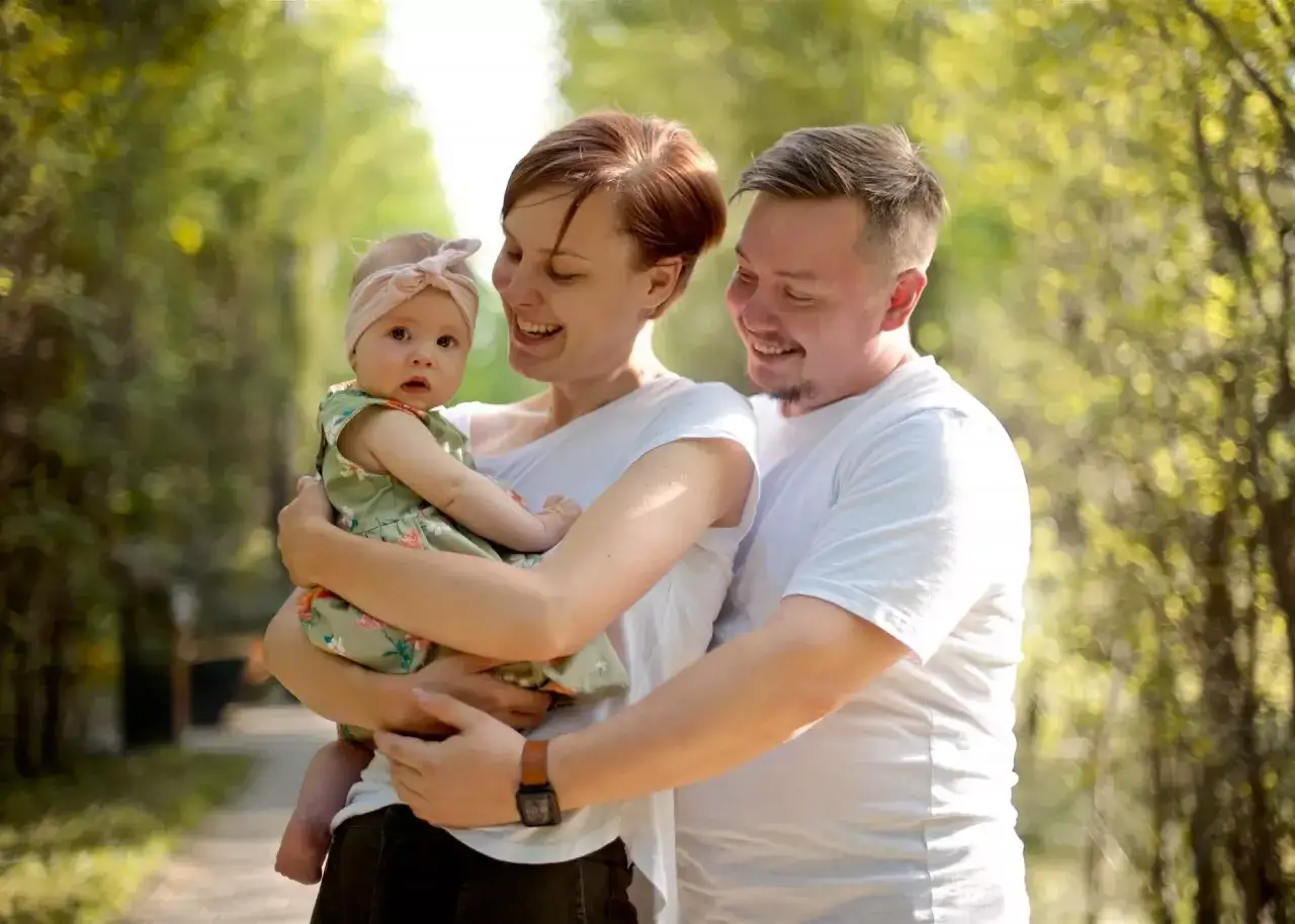 Szczęśliwa rodzina z niemowlęciem w parku. Dofinansowanie do żłobka do jakiego wieku? To pytanie nurtuje wielu rodziców.