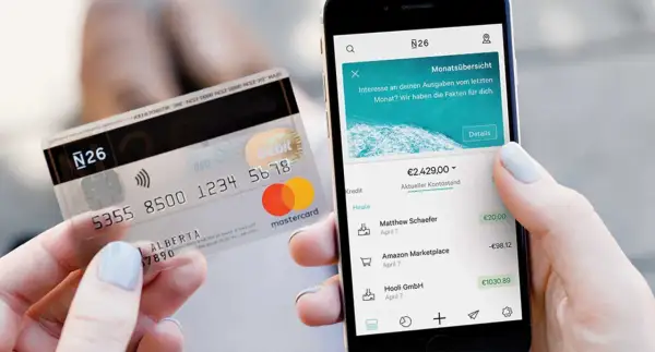 Karta N26 i smartfon z aplikacją bankową pokazującą saldo konta i ostatnie transakcje.