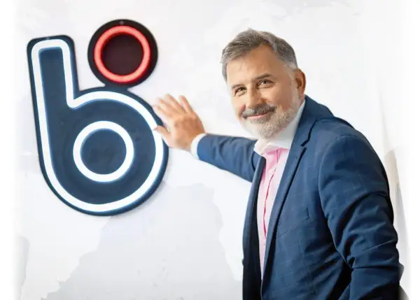 Mężczyzna w garniturze opiera się o logo, które może sugerować, kto wymyślił BLIK.