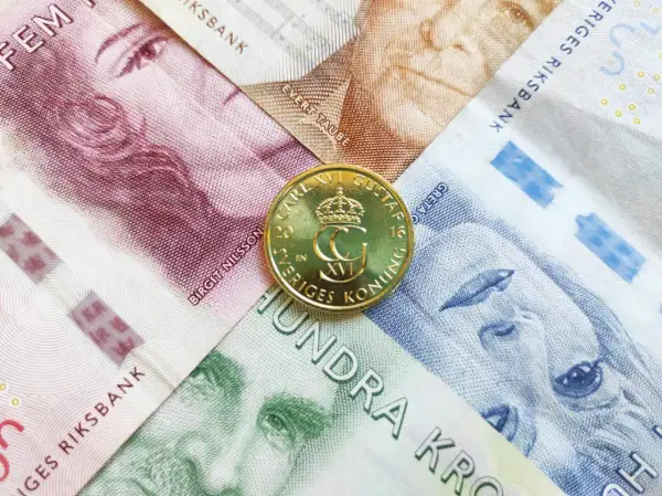 Szwedzka korona, czyli jaka waluta jest w Szwecji, widoczna na banknotach z portretami i złotej monecie z wizerunkiem króla Karola XVI Gustawa.