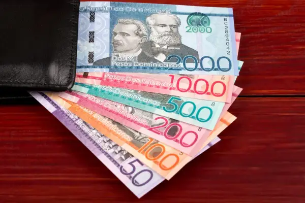 Dominikańskie pesos w różnych nominałach wychodzące z czarnego portfela.
