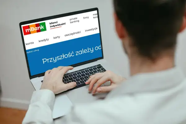 Mężczyzna korzysta z laptopa z logo mBank. Na ekranie widnieje hasło "Przyszłość zależy od..." i opcje takie jak konta, kredyty, karty, oszczędności, inwestycje. To idealne miejsce do zarządzania przelewami mBank.