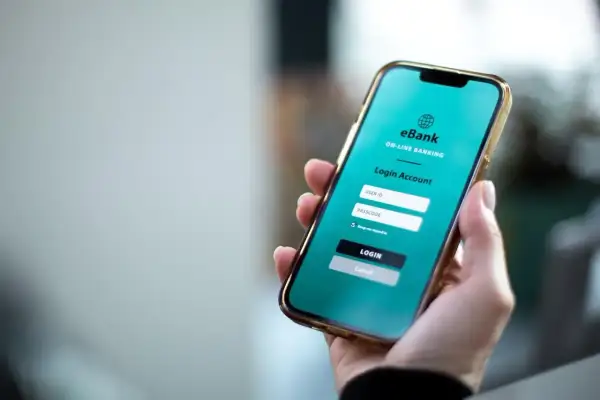 Dłoń trzyma smartfon z ekranem logowania do bankowości internetowej. Można tu wykonać przelewy wychodzące PKO BP.